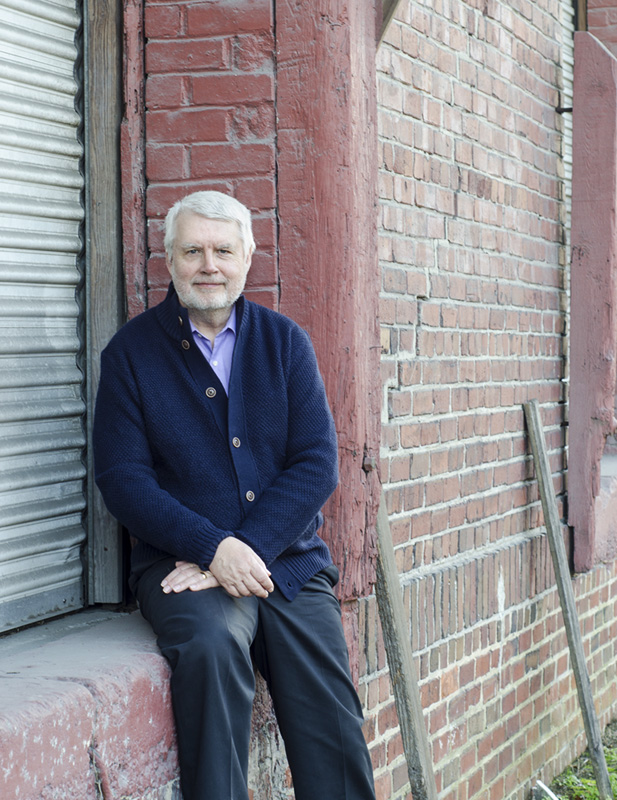 man sitting white hair beard brick building